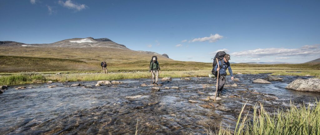 Randonneurs traversant une rivière en montagne