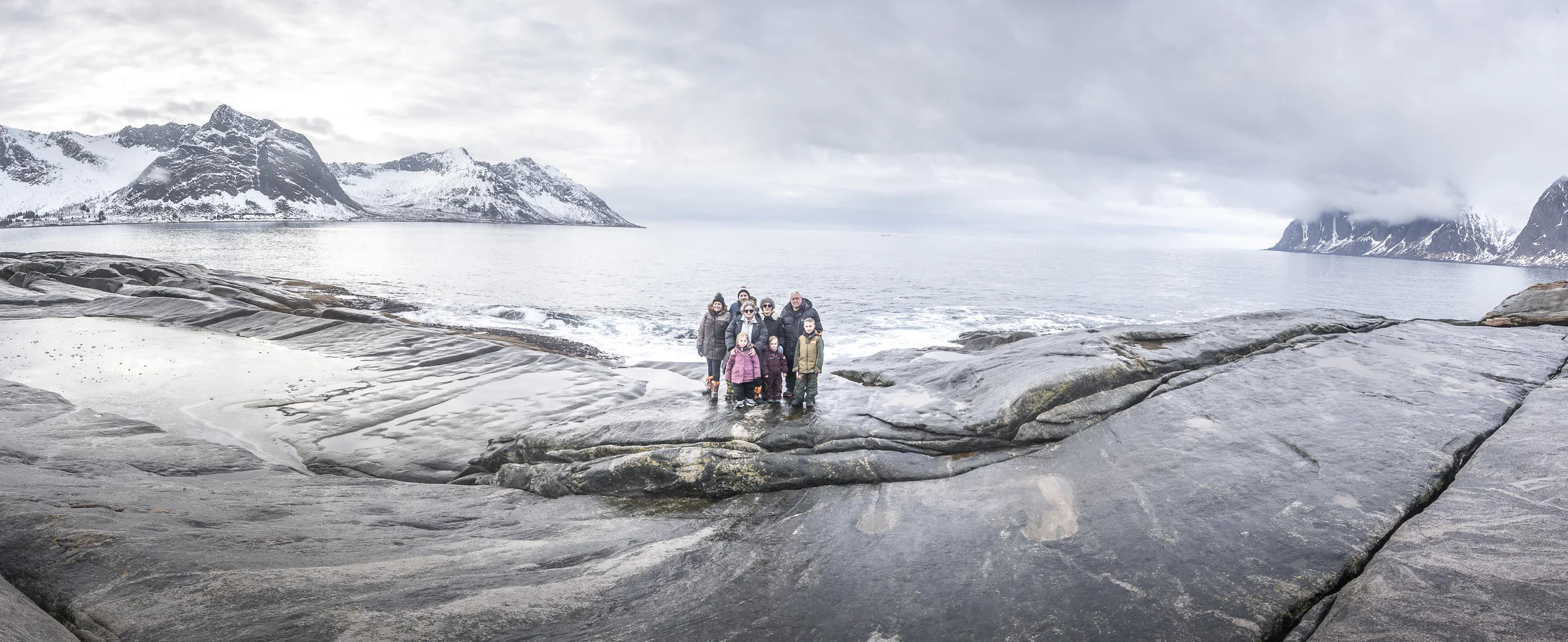 Famille sur les rochers face aux sommets de l'île de Senja
