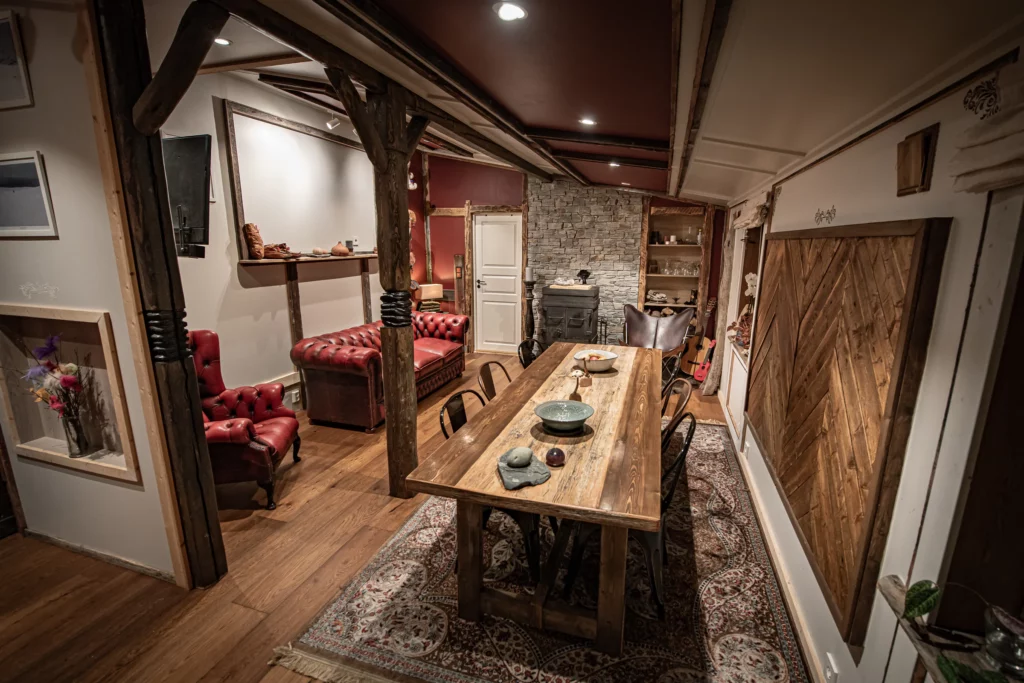 Salle à manger avec grande table en bois et canapé en cuir rouge
