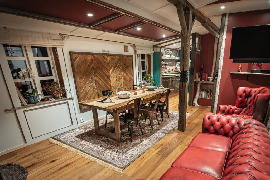 Salon et salle à manger avec mur en bois à chevrons et canapé chesterfield